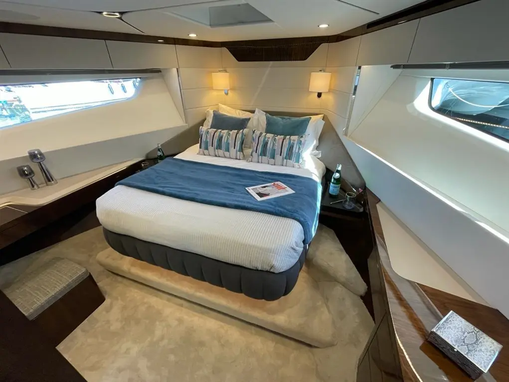 Luxurious yacht cabin featuring a king-size bed, stylish decor, and large windows, complemented by a glass of water and a magazine.
